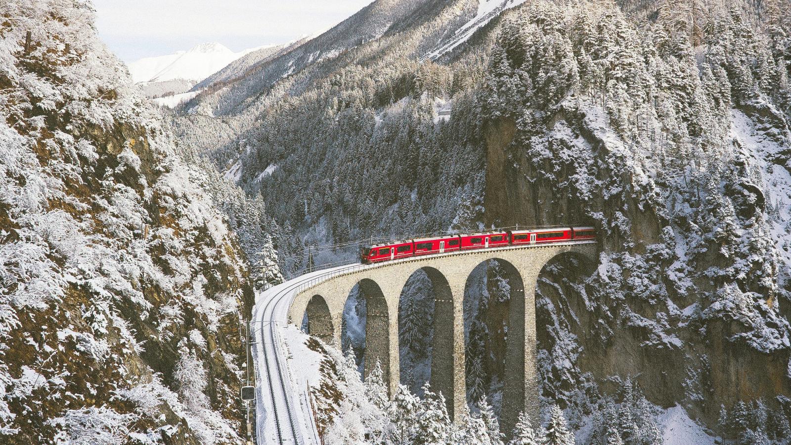 Swiss train passing over a bridge through the mountains